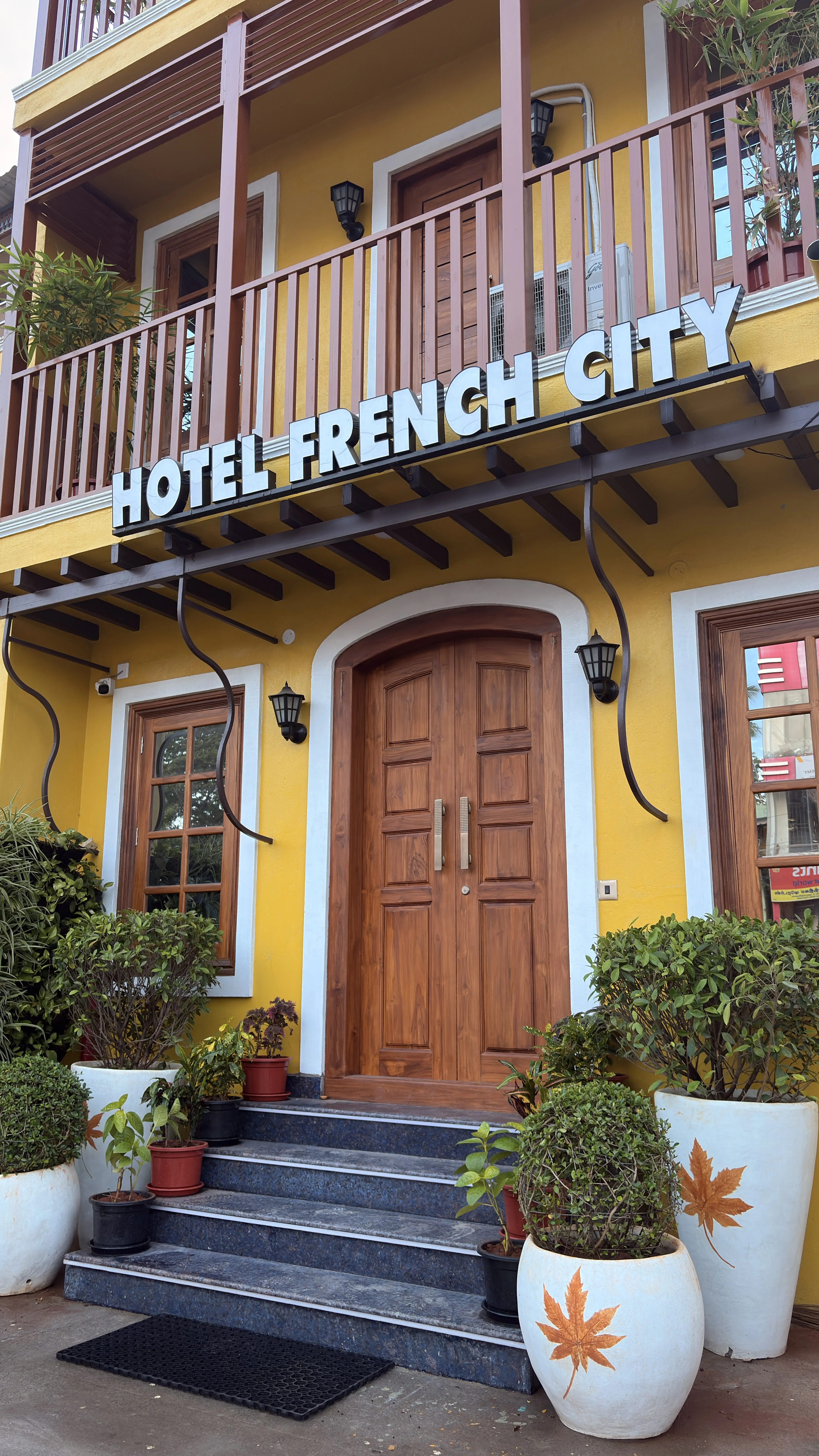 Yellow facade and wooden entrance doors of Hotel French City
